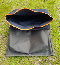 Load image into Gallery viewer, The opening of the Midwater Chair Tidy in black and mad orange and one lay on the grass in olive green