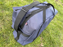 Load image into Gallery viewer, A large competition blue Midwater Carryall from above showing carry handles and a shoulder strap, on a grassy field.