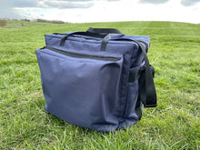 Load image into Gallery viewer, A large competition blue Midwater Carryall with carry handles and a shoulder strap, showing external pocket, placed on a grassy field.